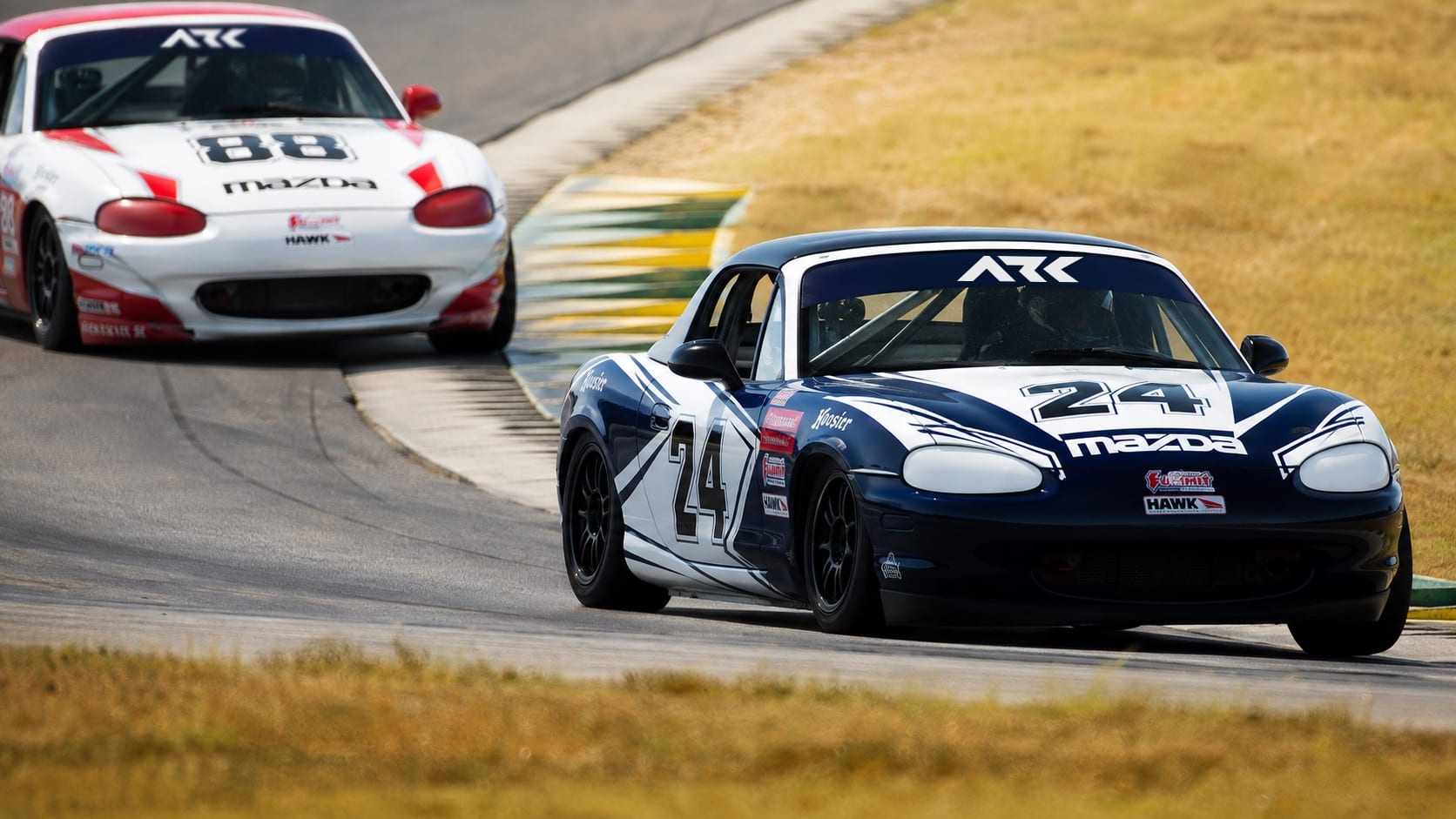 Spec Miata race cars running side by side on circuit